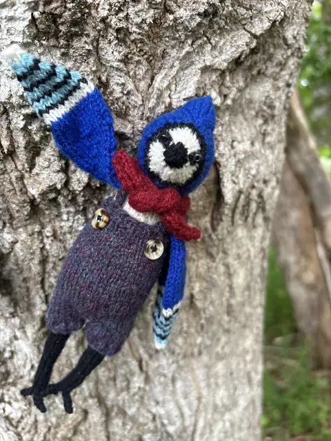 Hand-knitted blue and purple bird with striped wings